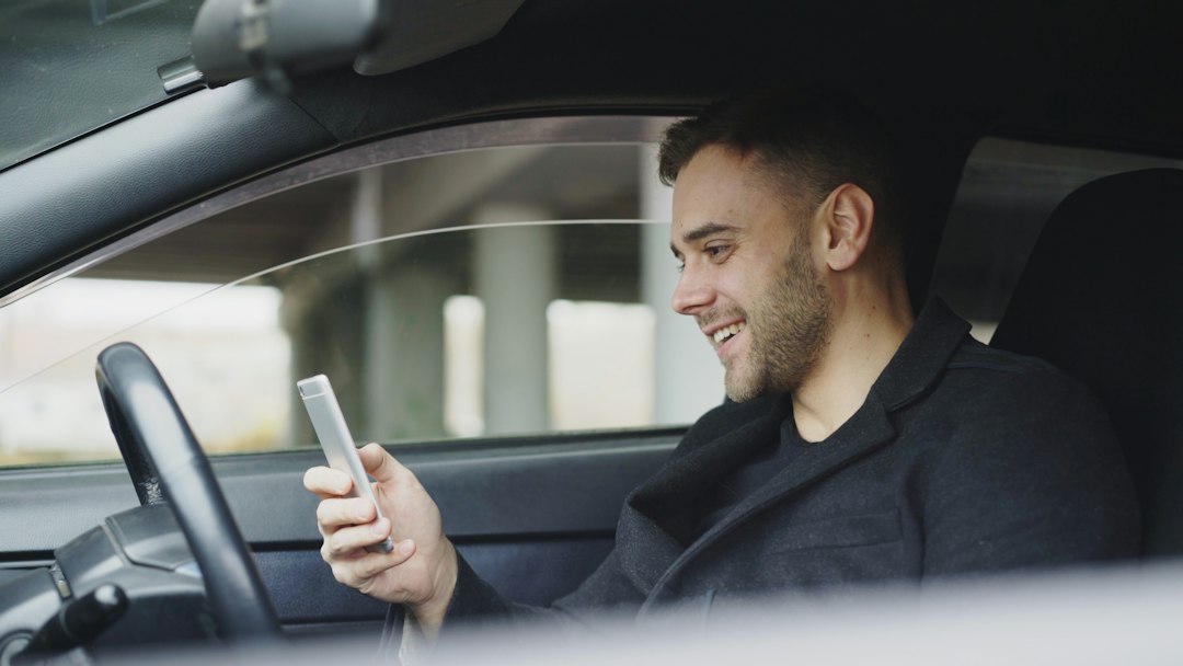 Motorista sentado no carro olhando o celular